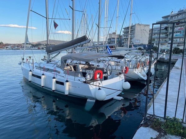 A marina with several sailboats docked, featuring a calm water surface and a clear sky.