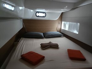 A compact bed with a headboard, two pillows, and two red pillows.