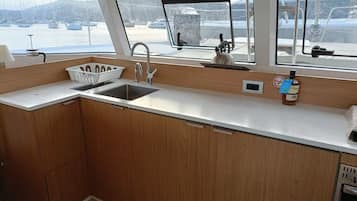 Una piccola cucina lineare con lavandino, pensili e oblò che offre vista sul porto turistico.