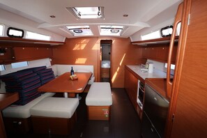 A compact interior with a dining area, bench seating, a small kitchenette, and a door leading to a closet. - Sun-Kissed Sailing Adventure in Split, Croatia (Kaštel Gomilica)