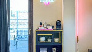 A room with a neon sign reading 'Coffee' above a shelf with a coffee machine, sugar, and a tea container. - Secret Rooftop Suite – Tor Vergata Metro (Roma)