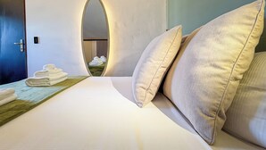 A hotel room with a bed, pillows, a mirror, and a door. - Secret Rooftop Suite – Tor Vergata Metro (Roma)