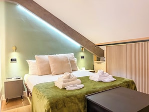 Una habitación de hotel con una cama, una mesita de noche y un pequeño escritorio con una lámpara.