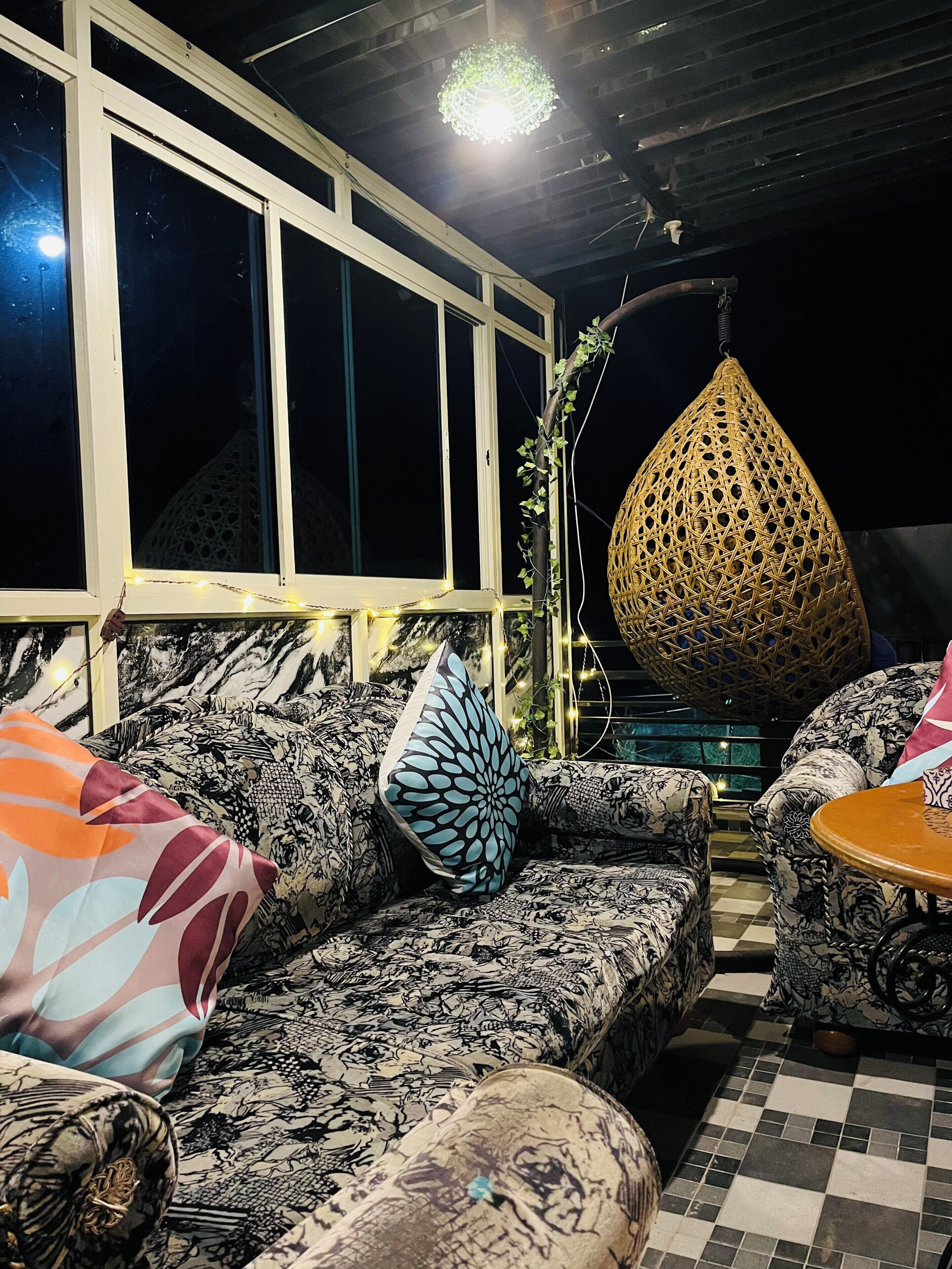 Un espace extérieur aménagé avec des canapés à motifs, un fauteuil suspendu et un sol à carreaux.