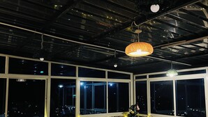 A room with a checkered floor, a patterned sofa, a dining table, and a large window with a view of the city at night.