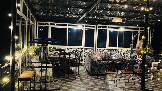 An outdoor covered patio with a checkered floor, seating arrangements, and string lights.