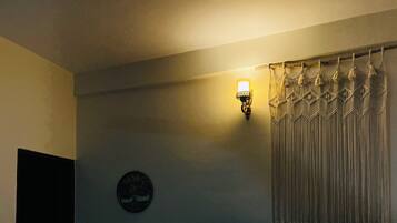 Un dormitorio con cama, ventilador de techo, lámpara de pared y cortina.