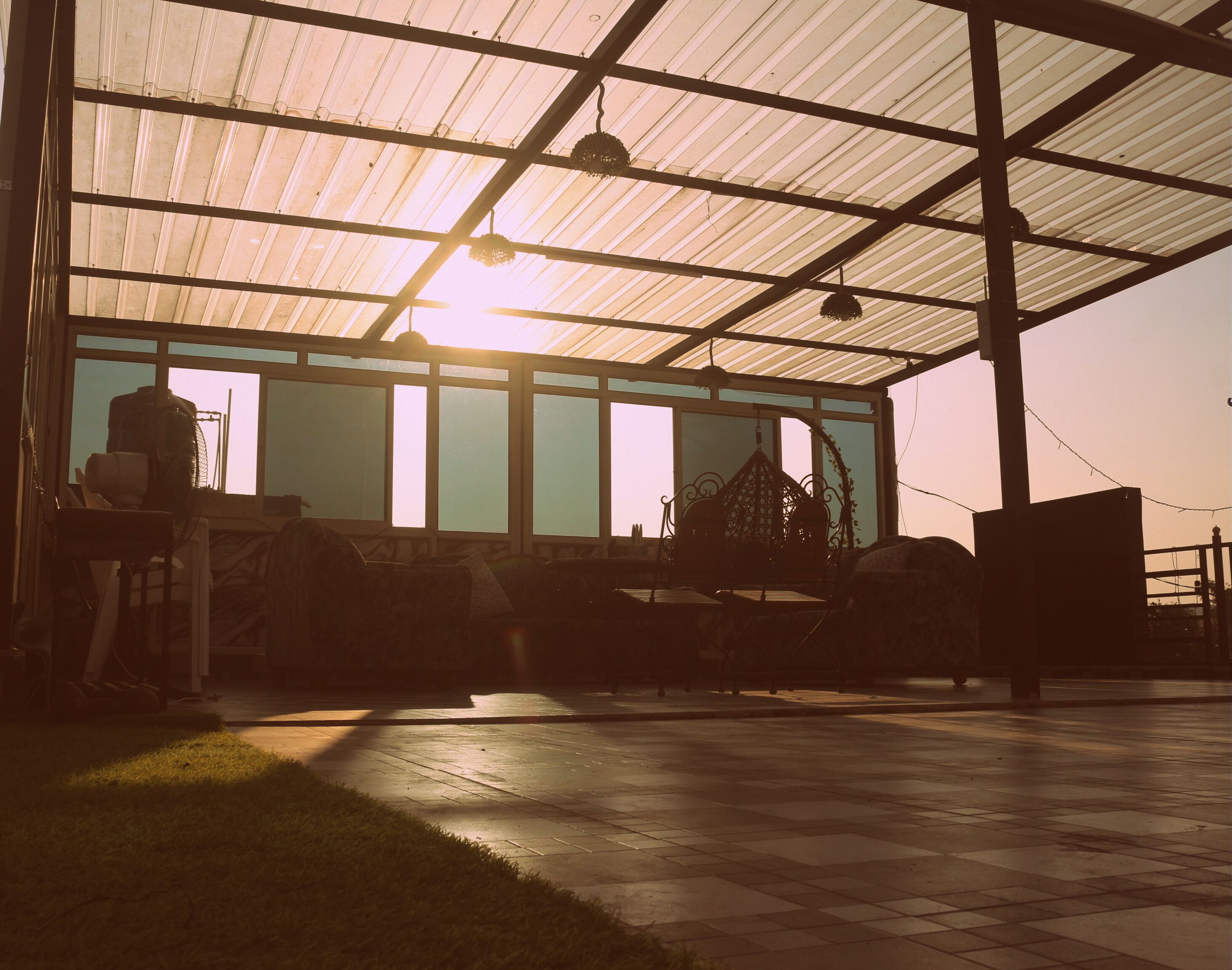 A covered outdoor area with a metal roof, a bench, and a table with chairs.