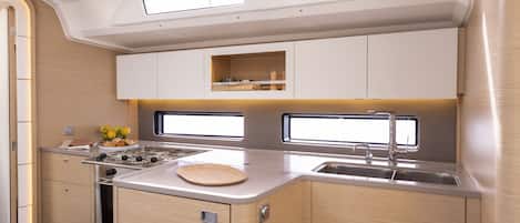 A compact kitchen with a stove, sink, and upper cabinets.