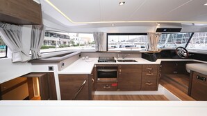 A compact kitchen with a built-in oven, a sink, and a window with curtains. - Sun-kissed Sailing Adventure in Split-Dalmatia, Croatia (Trogir)