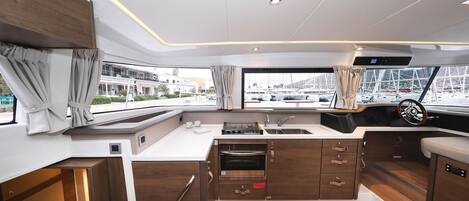 Cocina compacta con horno integrado, pileta y ventana con cortinas.