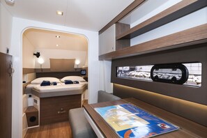 A compact interior with a bed, a table with a magazine, and a window with a view of a snowy landscape. - Sun-kissed Sailing Adventure in Split-Dalmatia, Croatia (Trogir)