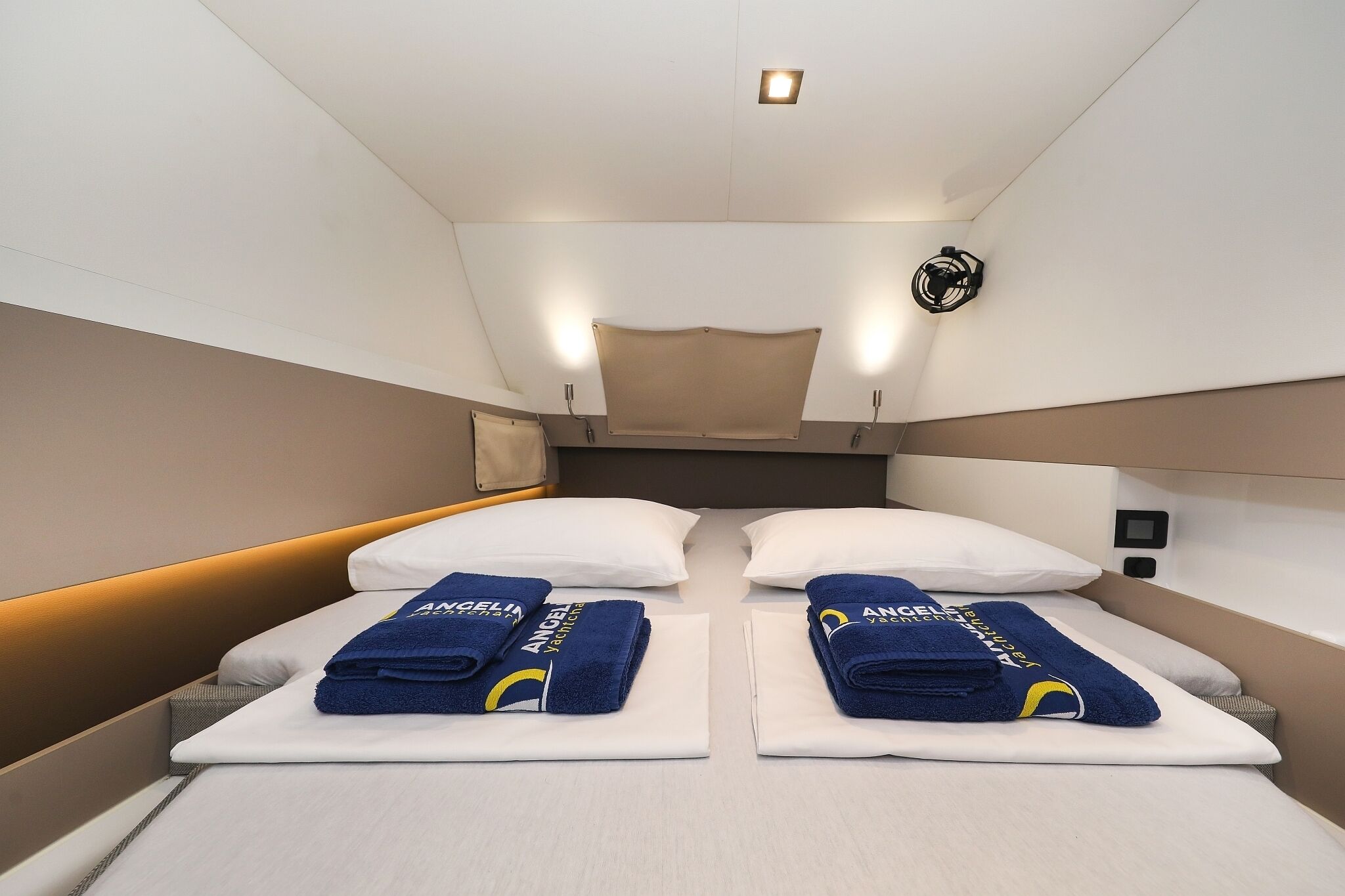 A hotel room with two beds, each with a white mattress and blue towels.