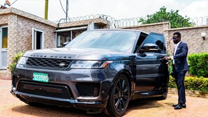 Un Range Rover estacionado frente a un edificio de fachada de ladrillo y alambre de púas en la parte superior.