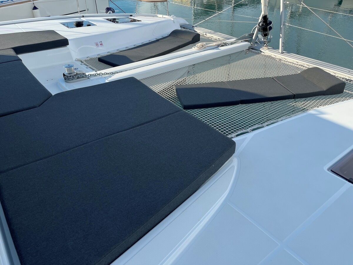 A boat deck with cushioned seating areas and a metal railing.