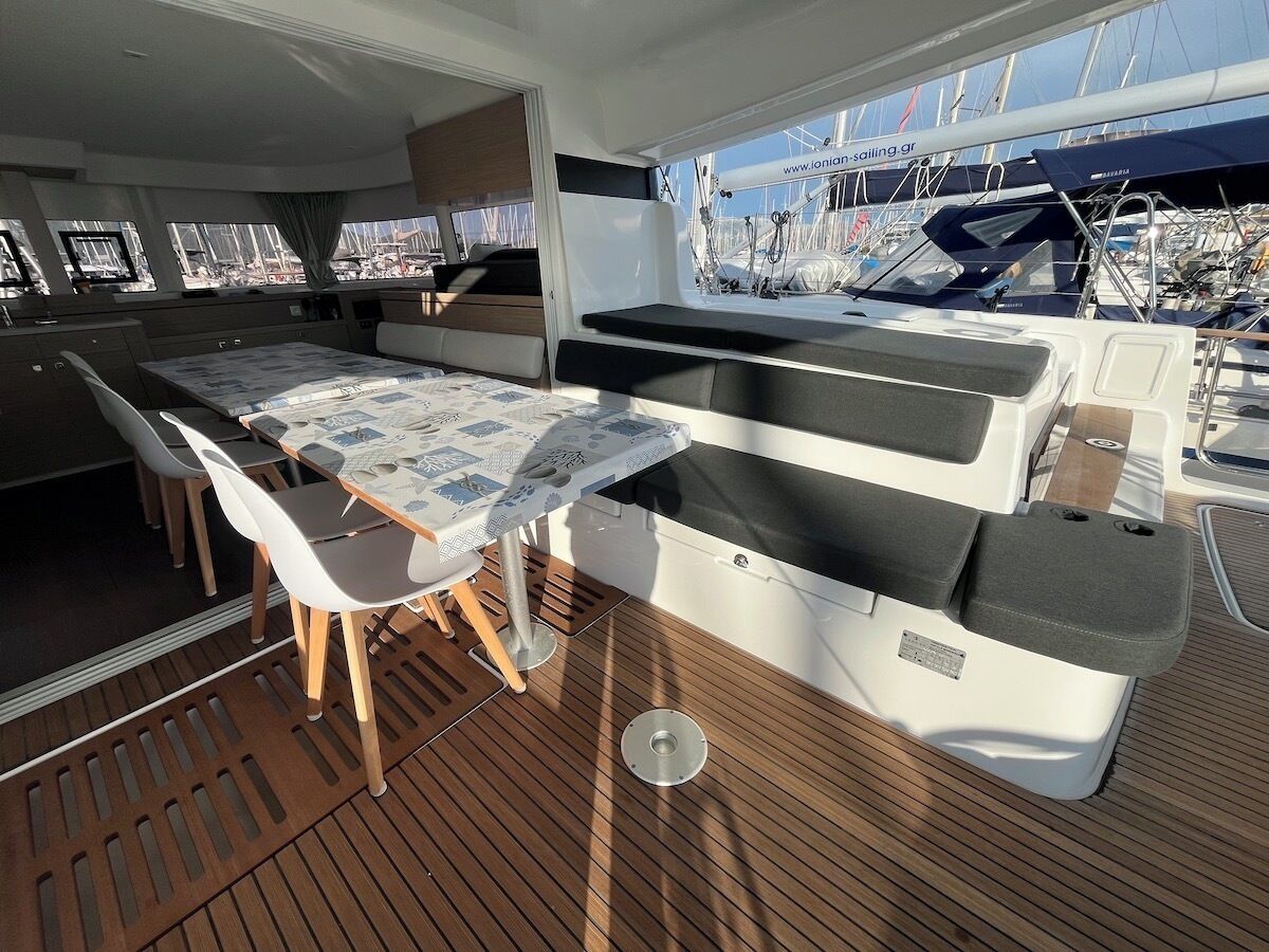 A sunlit deck with a table and chairs, a view of the marina, and a control station.