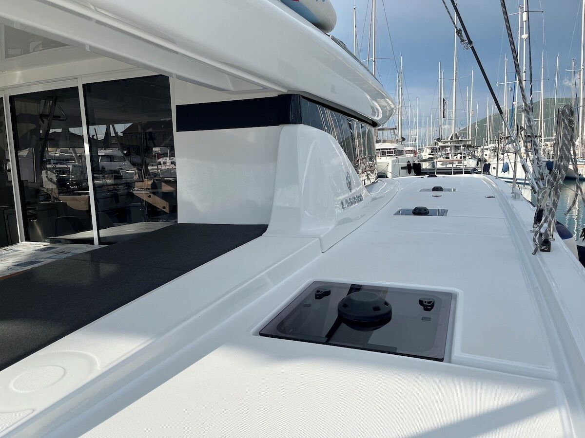 A boat deck with a seating area, a control panel, and a view of other boats in the marina.