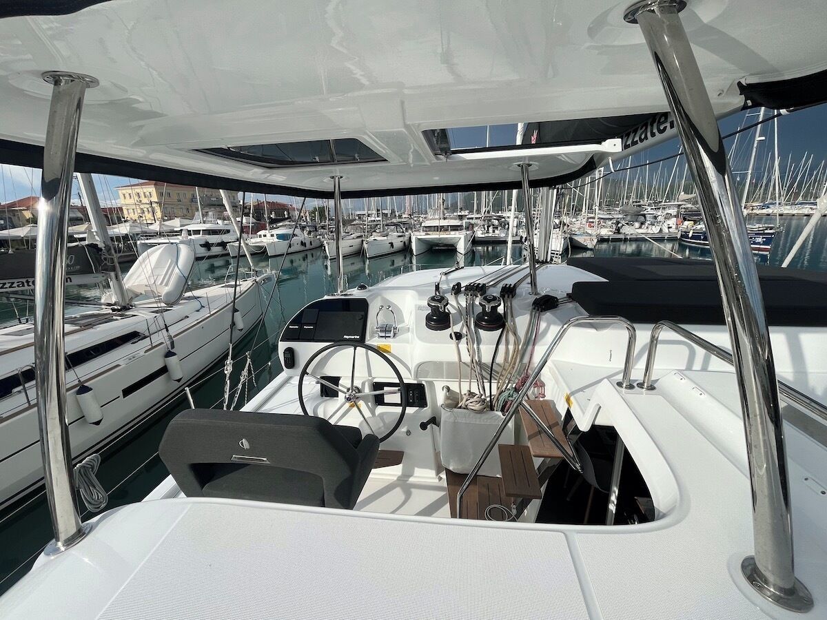 A boat deck with a steering wheel, control panel, and various navigational equipment.