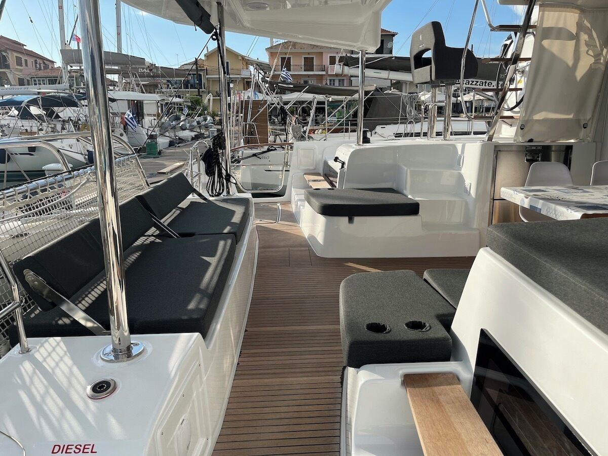 A boat deck with seating areas, a wooden floor, and a marina in the background.