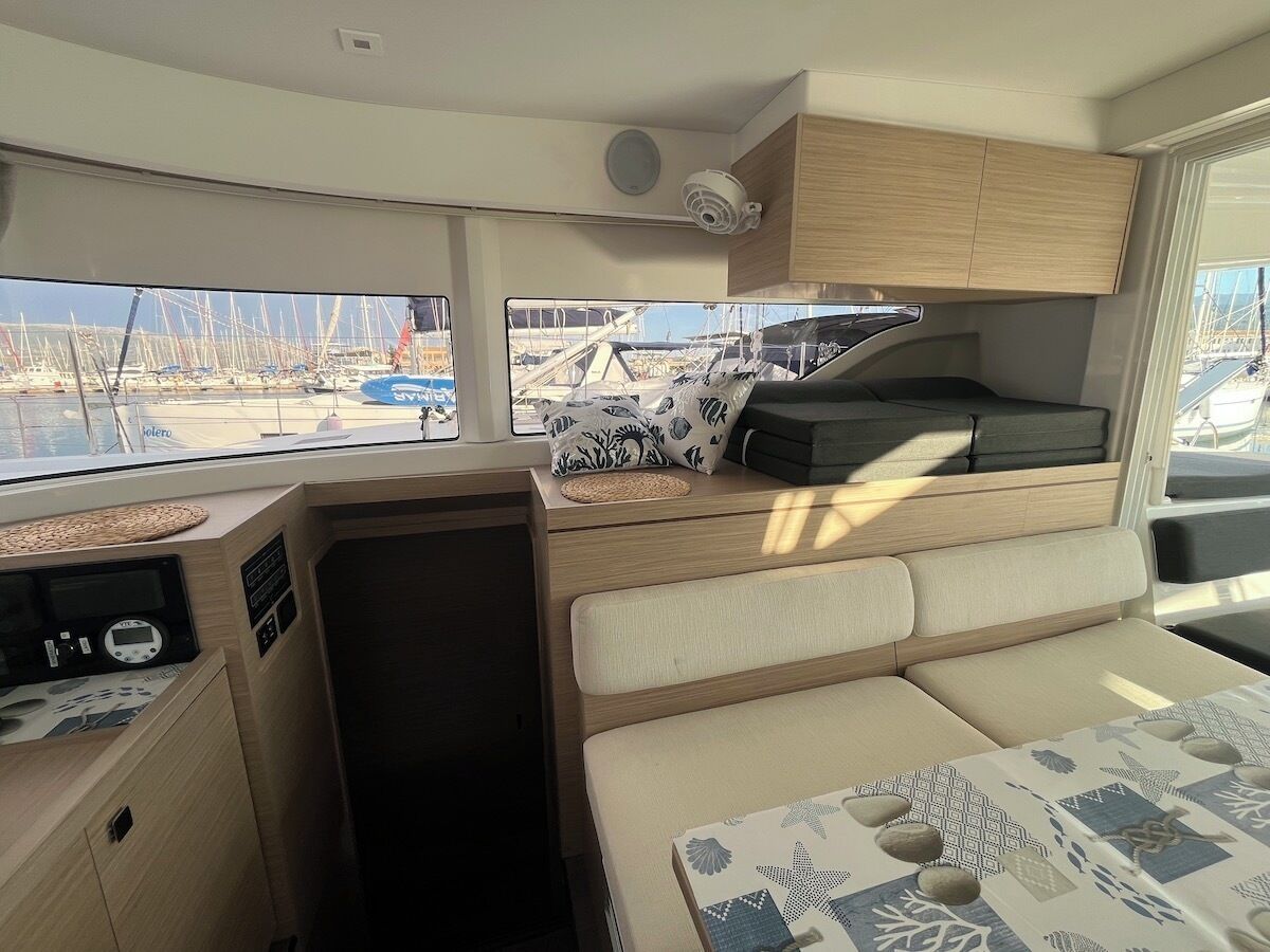 Ein kompaktes Wohnmobil-Interieur mit Küchenzeile, Sitzgelegenheit und Blick auf den Yachthafen.
