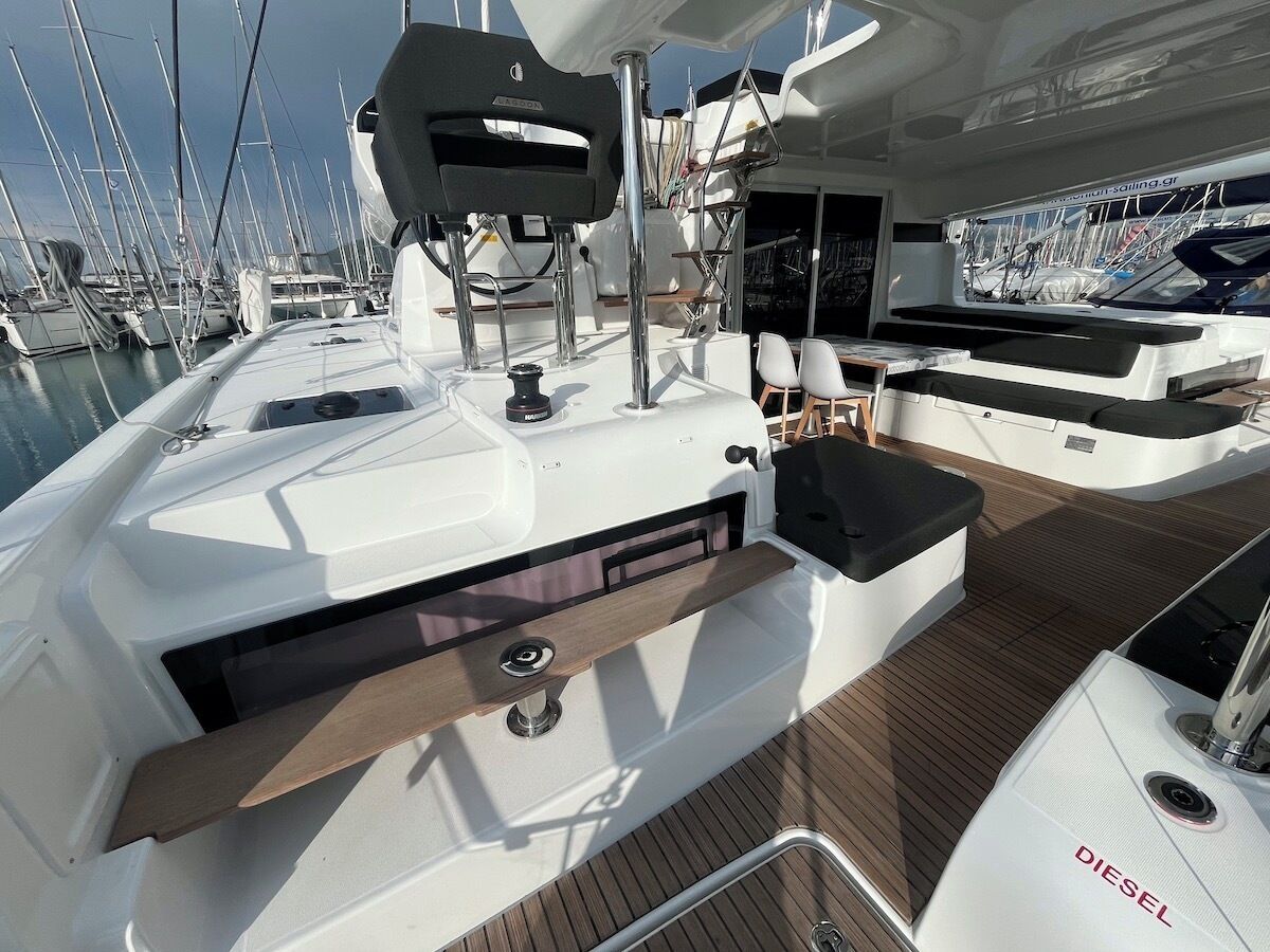 A yacht deck with a seating area, a control panel, and a view of other yachts in the marina.