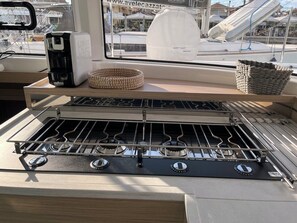 A kitchen with a gas stove, a coffee maker, and a basket. - Sun-Kissed Sailing Adventure in the Ionian Islands, Lefkada (Lefkada)
