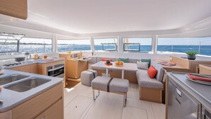 A modern galley with a sink, stove, and dining area with a view of the sea. - Sun-kissed Sailing Adventure in the Ionian Islands (Preveza)