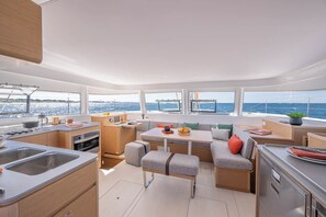 A modern galley with a sink, stove, and dining area with a view of the sea. - Sun-kissed Sailing Adventure in the Ionian Islands (Preveza)
