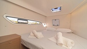 A compact, well-lit room with a bed, a small bedside table, a window with a view, and a built-in mirror. - Sun-kissed Sailing Adventure in the Ionian Islands (Preveza)