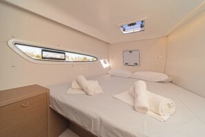 A compact, well-lit room with a bed, a small bedside table, a window with a view, and a built-in mirror. - Sun-kissed Sailing Adventure in the Ionian Islands (Preveza)