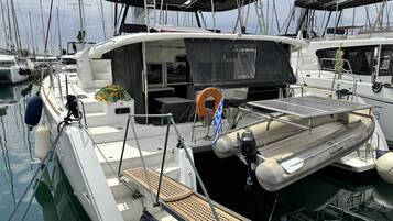 A marina with multiple sailboats docked, featuring lifeboats, a covered seating area, and a solar-powered charging station.
