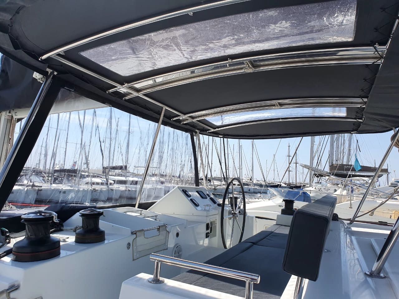 A boat deck with a steering wheel, winches, and a canopy.