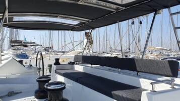 A boat deck with a covered seating area, a steering wheel, and a winch labeled 'HARKEN'.