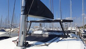 A sailboat with a covered deck and multiple masts, docked in a marina with other boats. - Sun-Kissed Sailing Adventure in Islas Sarónicas (Alimos)