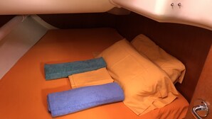 A small, compact bed with an orange mattress and pillows, a blue blanket, and a purple blanket. - Sun-Kissed Sailing Adventure in the Majestic Islas Baleares (Sant Antoni de Portmany)