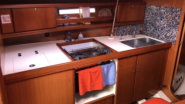 A compact kitchenette with a sink, stove, and storage cabinets. - Sun-Kissed Sailing Adventure in the Majestic Islas Baleares (Sant Antoni de Portmany)