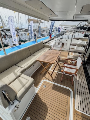Ein Jachtdeck mit einer Couch, einem Tisch und Stühlen.