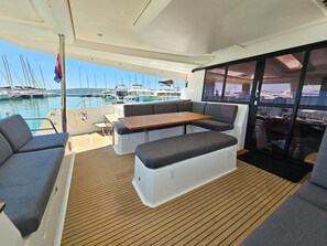 Ein Yachthausdeck mit Sitzgelegenheiten, einem Tisch und Blick auf den Hafen.