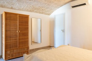 Ein Schlafzimmer mit großem Kleiderschrank, einem Bett, einem Spiegel und einer Tür.