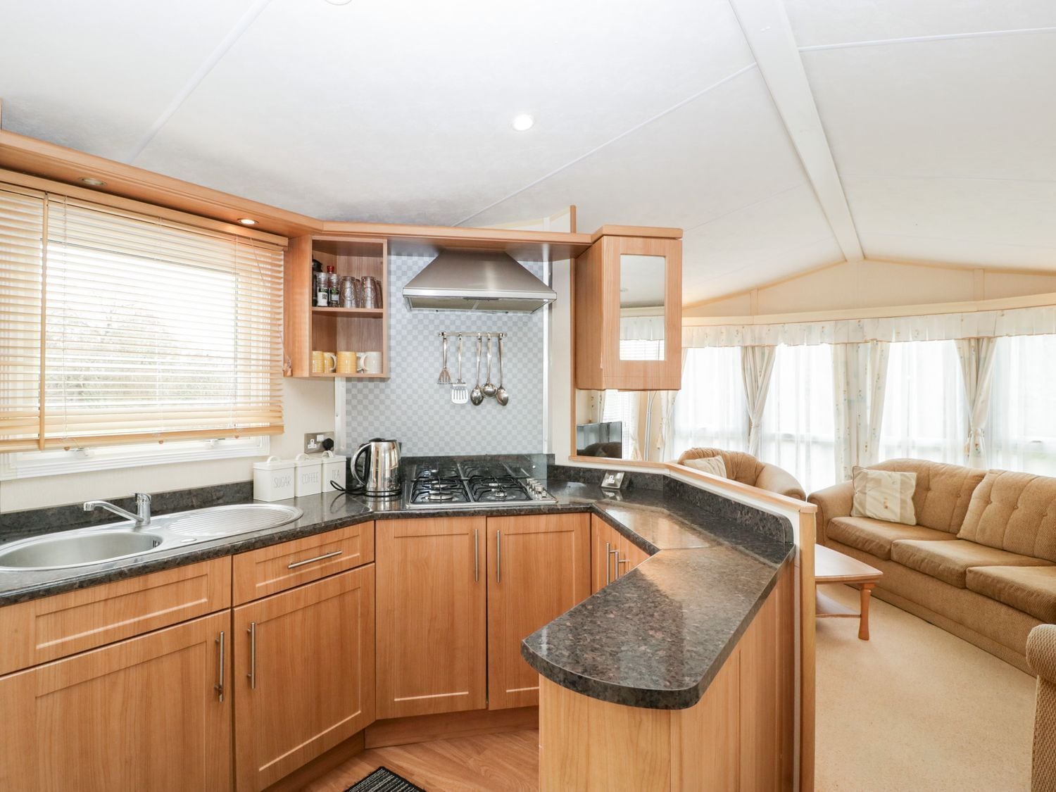 Une cuisine de taille réduite, avec des meubles de rangement en bois, une cuisinière à gaz et un évier.