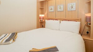 Habitación de hotel con una cama grande, cabecera de madera, mesitas de noche y cuadros en la pared.