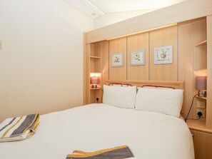 Ein Hotelzimmer mit einem großen Bett, einem Holzkopfteil, Nachttischen und einem gerahmten Kunstwerk an der Wand.