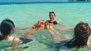 Helder turquoise water met overwater bungalows op de achtergrond.