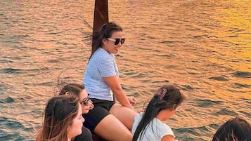 Un grupo de personas en un bote con un atardecer de fondo.