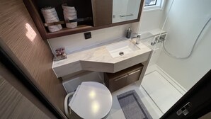 A bathroom with a white sink, a mirror, a towel rack, and a shower. - Sun-Kissed Sailing Adventure in Islas Sarónicas (Alimos)
