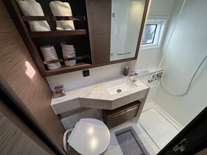Een badkamer met een witte wastafel, een spiegel, een handdoekhouder en een douche.