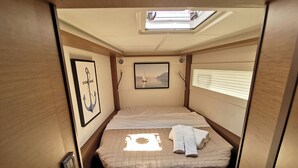A compact, well-lit interior with a bed, a framed picture, and a skylight. - Sun-Kissed Sailing Adventure in Islas Sarónicas (Alimos)
