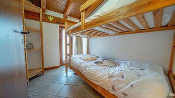 A single-bed room with a wooden ceiling and a window.