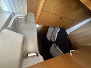 Ein kompakter Innenraum mit Toilette, kleinem Waschbecken und Holzschrank.