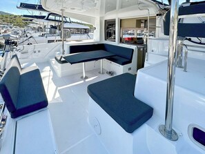 A boat's deck with a seating area, a table, and a view of other boats in the marina. - Sun-Kissed Sailing Adventure in Sibenik, Croatia (Primošten)